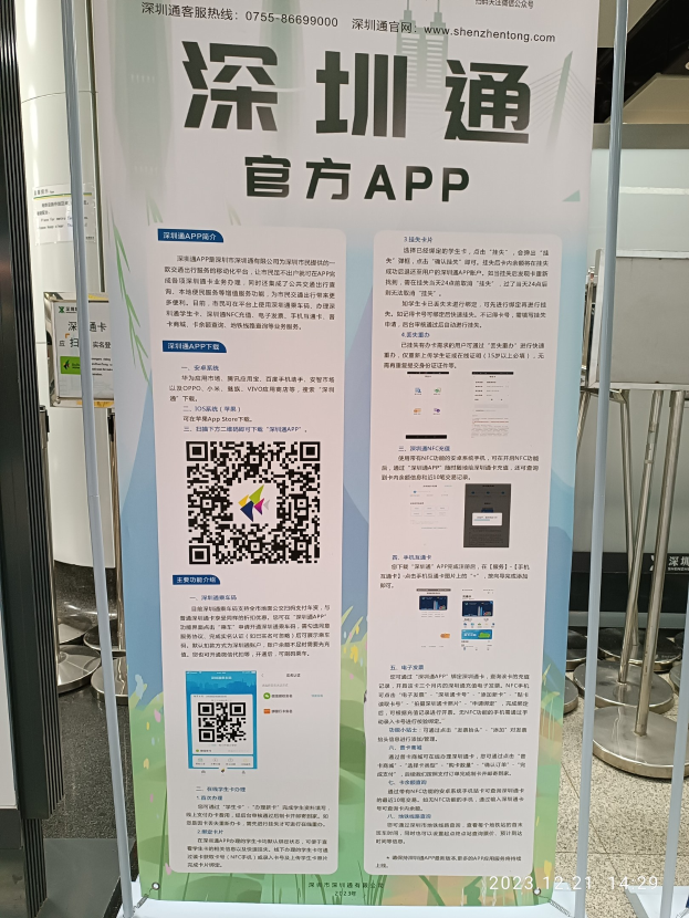Ein Banner mit einem QR-Code vor einem Gebäude, umgeben von verschiedenen Ständen, Tafeln und Gegenständen, wahrscheinlich für den Shenzhen International Airport.