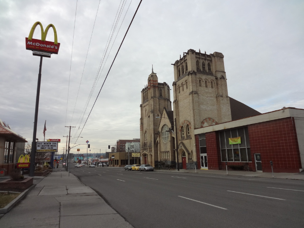 Eine Straßenansicht mit Gebäuden auf der rechten Seite, Pfählen und Autos in der Mitte und einer McDonald's-Pfahl auf der linken Seite.
