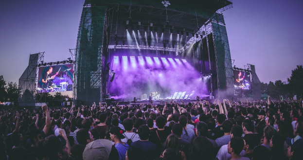 Schwarzes und weißes Foto von Wagners Opernhaus in Bayreuth mit Menschen vorne, umgeben von Bäumen und einem klaren Himmel, mit Text unten.