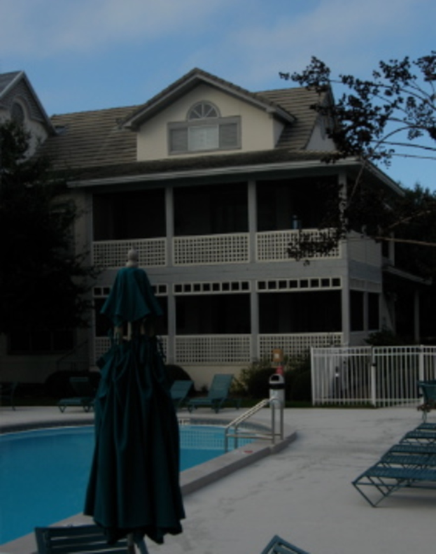 Ein Schwimmbad links, ein Gebäude in der Mitte und der Himmel oben.