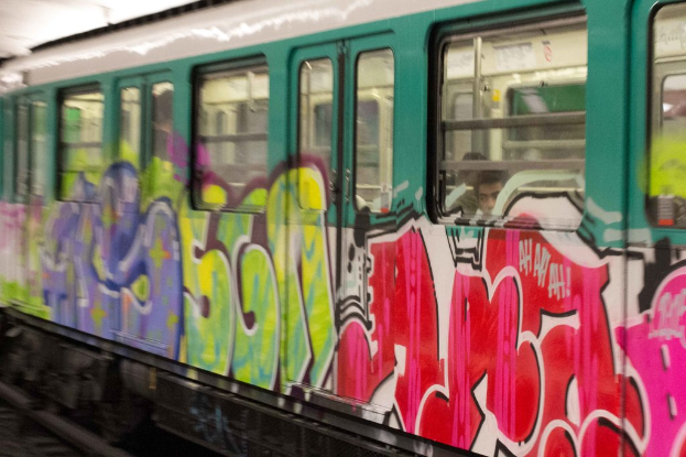 Ein Zug auf Schienen mit zwei Personen im Inneren und Graffiti an seiner Außenseite.