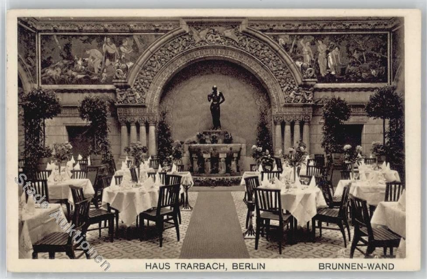 Ein altes Schwarz-Weiß-Foto eines Berliner Restaurants mit Tischen, Stühlen, Blumenvasen, einer Statue, Skulpturen und Pflanzen an den Wänden, mit Text unten.