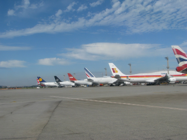 Eine Start- und Landebahn mit wenigen Flugzeugen, Masten, Kabeln und einer bewölkten Himmel.
