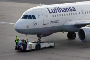 Ein Lufthansa Airbus A319-100 auf dem Rollfeld am Frankfurter Flughafen, mit einem Fahrzeug und einer Person in der Nähe, bereit zum Start.