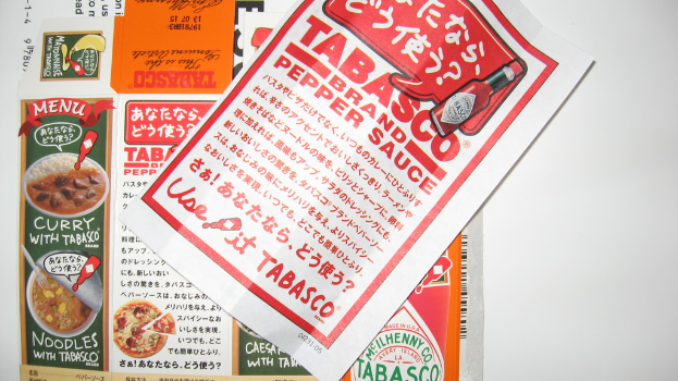 Ein Prospekt, das Pfeffersoße bewirbt, mit einem darunter liegenden Blatt, auf dem Curry-Anzeigen zu sehen sind.