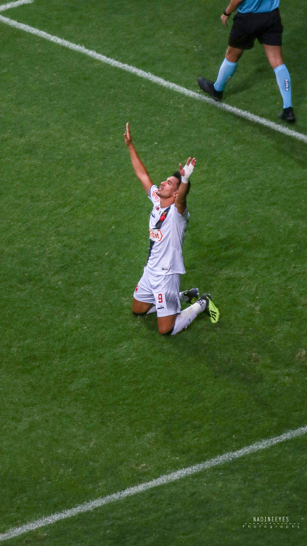Ein Fußballer in Uniform kniet auf dem Boden mit ausgestreckten Armen in Feierlaune.