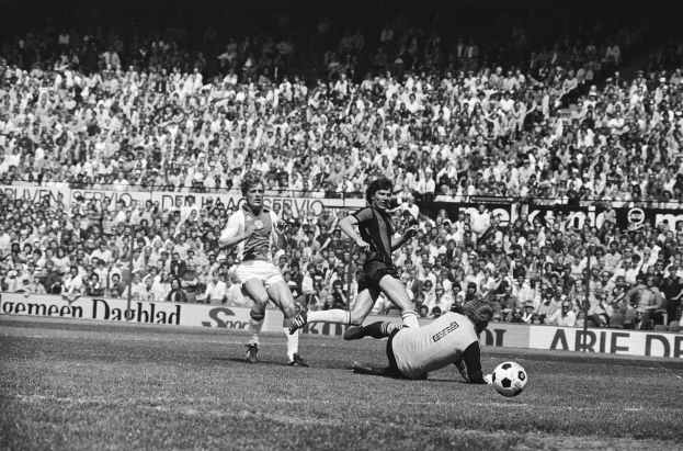 Schwarzes Foto von Fußballspielern im Einsatz auf einem Feld mit Zuschauern im Hintergrund und einer Bundesliga 1978-79 Ajax vs. Hannover 96-Tafel.