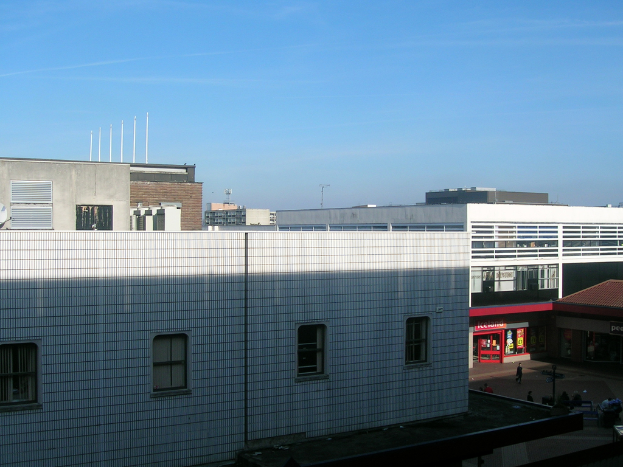 Eine Straßenansicht mit Gebäuden und Geschäften und einigen Menschen, die dazwischen gehen.