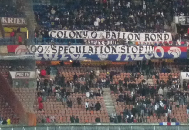 Ein Stadion voller Menschen, Banner und StÃ¼hle, mit einem Zaun unten und einer Treppe links.