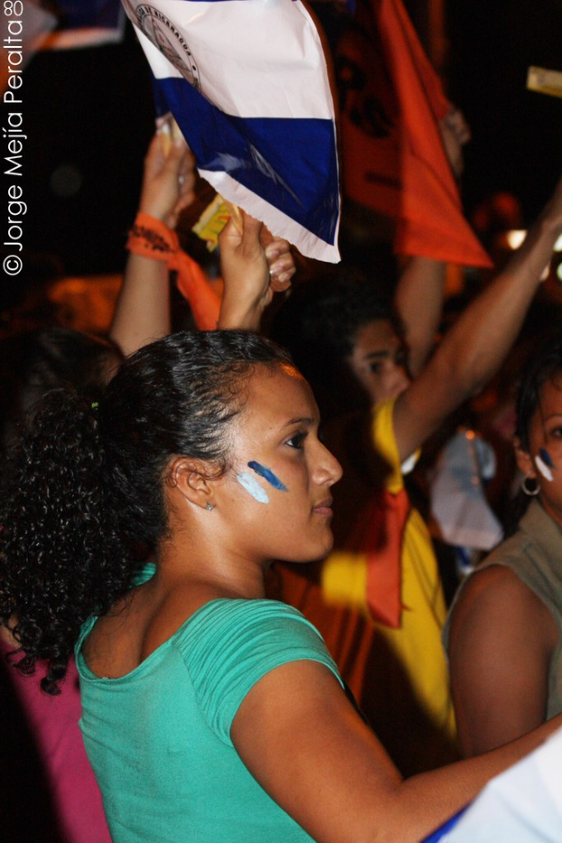 Frauen in grünen T-Shirts bei einer Demonstration, die weiße Decken halten, mit mehr Mädchen dahinter.