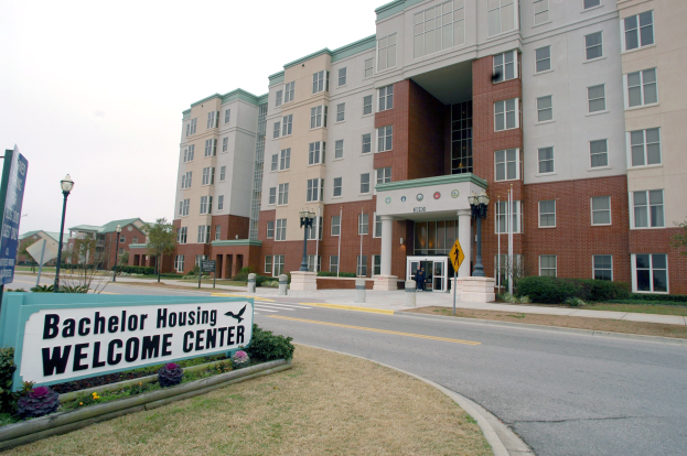 Ein Willkommenszentrum für Bachelor-Unterkünfte mit Gebäuden, Straßeninfrastruktur, Fahrzeugen, Grünflächen und einem klaren Himmel.