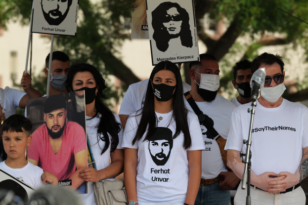 Menschen mit Masken halten Schilder auf einer Demonstration in Mexiko-Stadt, mit Mikrofon, Kamera und Menge.