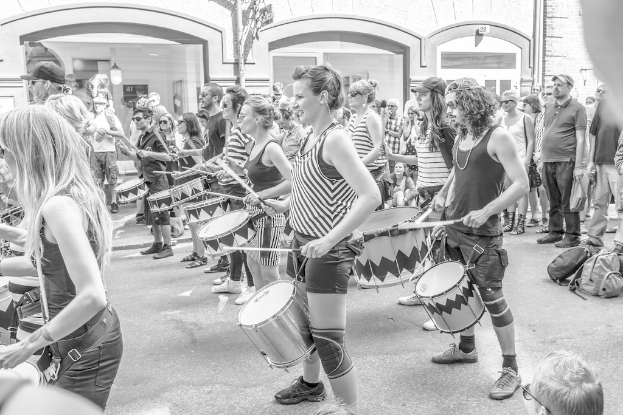 Eine Gruppe von Menschen, die Musikinstrumente im Freien spielen, mit einer geschlossenen Glastür und einem Licht im Hintergrund.