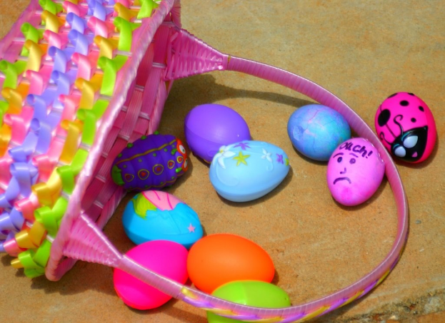 Ein geflochtenen Korb und einige farbenfrohe Ostereier auf einer Wand.