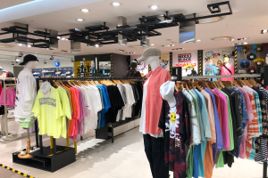 Ein Bekleidungsgeschöftsinnenraum mit Puppen in Kappen, Körper auf Bühgeln, Displaytafeln mit Text und Deckenlampen, das sich im Mall of Asia befindet.