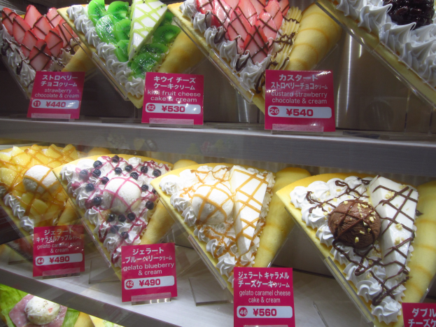 Vitrine mit verschiedenen Eissorten, die nach Farbe und Form sortiert sind und jeweils ein sichtbares Preisschild haben.