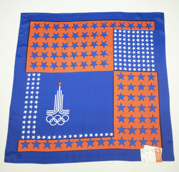 Ein blaues und orangefarbenes Bandana mit dem Olympischen Logo darauf, vor einem weißen Hintergrund.