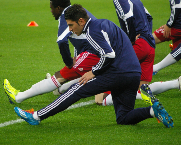Gruppe von Männern in Sportkleidung, die Fußball auf einem Rasenfeld während eines Trainings spielen.