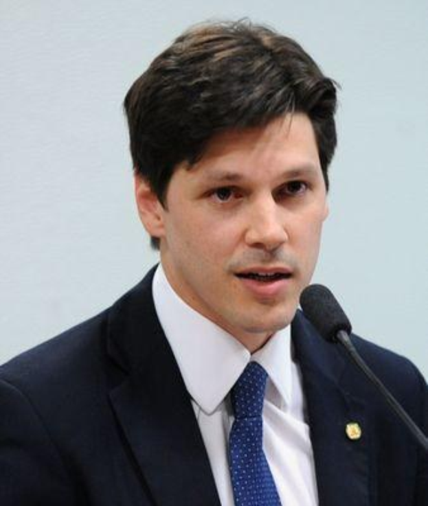 Ein Mann im Anzug und mit Krawatte spricht in ein Mikrofon an einem Rednerpult, wahrscheinlich um die Genehmigung eines Gesetzes durch die Regierung zu kommentieren.