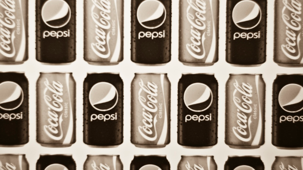 Zwei Sodadosen, eine Pepsi und eine Coca-Cola, sind nebeneinander gestellt.