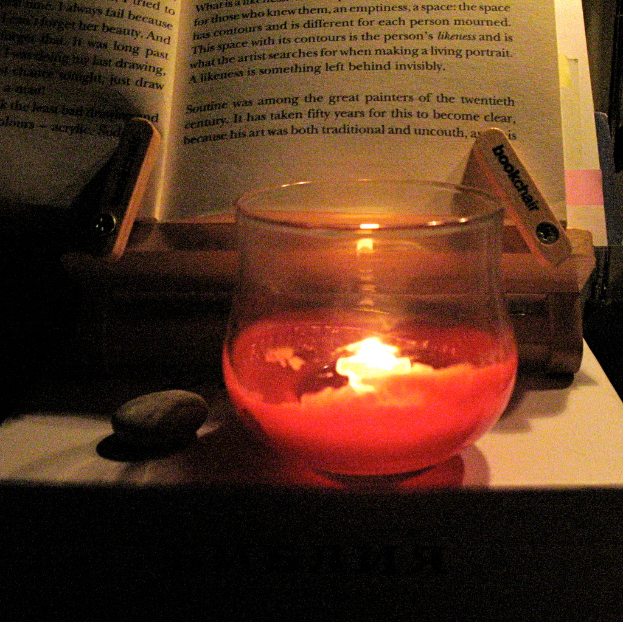 Ein Tisch mit Büchern, Kerzen, Gläsern, Text und einem Stein darauf.