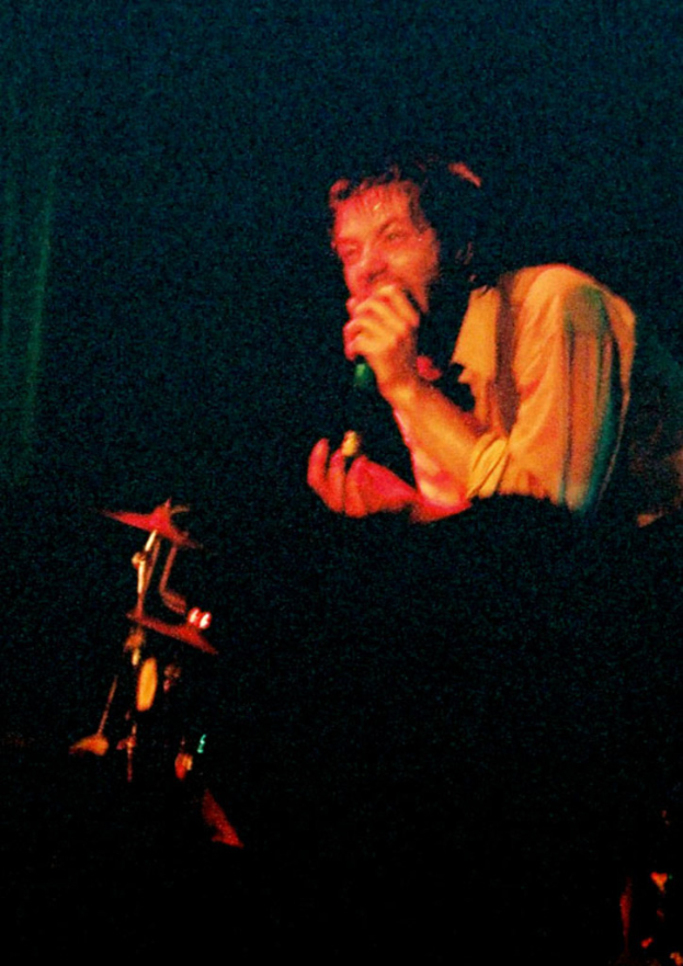 Ein Mann mit einem Mikrofon steht vor einer Band.