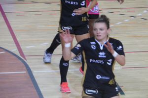 Eine Gruppe von Frauen in Sportkleidung beim Volleyballspielen auf einem Court.