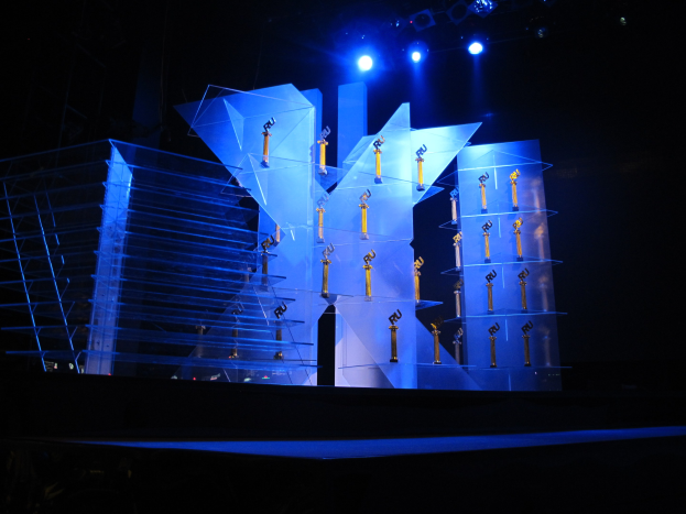 Eine Bühne für eine Preisverleihung mit dunklem Hintergrund, ein paar Lichtern und einigen Gegenständen, die mit dem Event in Zusammenhang stehen.