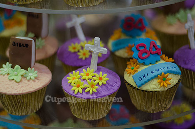 Ein Buch und ein heiliges Kreuzsymbol werden auf einen Cupcake gelegt, mit anderen Cupcakes im Hintergrund.