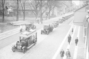 Ein Schwarz-Weiß-Foto einer Berliner Straße aus den 1930er bis 1940er Jahren mit Autos, Fußgängern, Gebäuden, Bäumen und einem klaren Himmel.