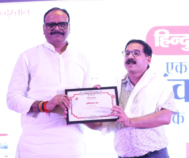 Zwei Männer mit Brille halten ein Zertifikat, vor einem Banner mit der Aufschrift "Maharashtra Tourism Awards 2019".