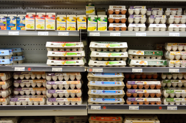 Ein Supermarktbord mit verschiedenen Eiersorten, jede mit einem Preisschild versehen.