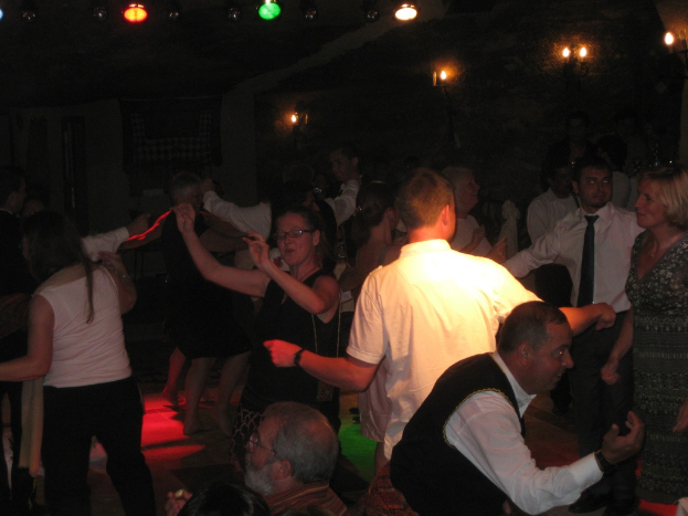 Eine lebendige Partyszene mit tanzenden Menschen auf der Tanzfläche unter verschiedenen Lichtern in einem dunklen Raum.