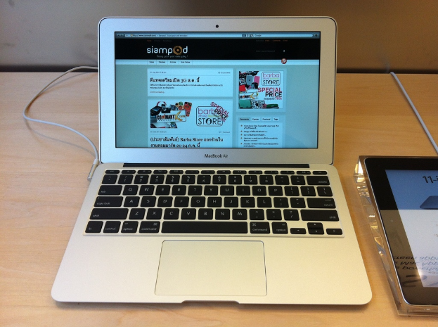 Ein Laptop und ein nicht identifiziertes Gerät sind auf einem Tisch platziert, mit Text und Cartoon-Bildern auf dem Laptop-Bildschirm.
