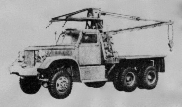 Ein Schwarz-Weiß-Foto eines großen, vierrädrigen Trucks mit einem Kran auf der Rückseite und einem Anhänger