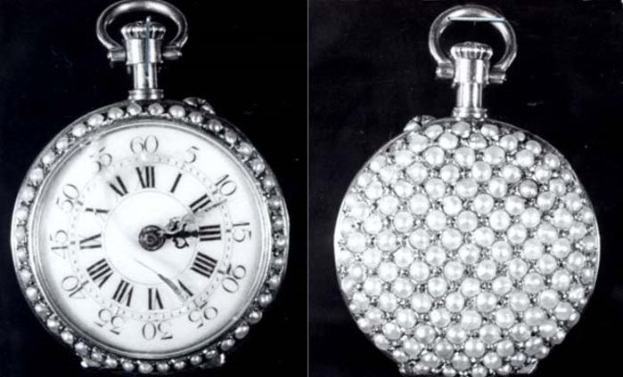Eine silberne Taschenuhr mit darin eingearbeiteten Diamanten, die ein rundes Zifferblatt mit römischen Zahlen zeigt, vor einem schwarzen Hintergrund.