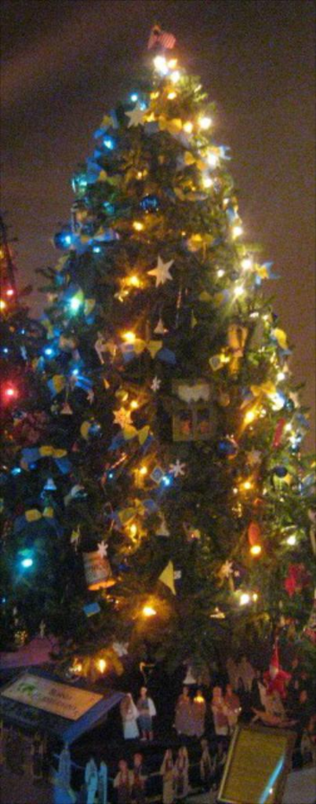 Ein geschm├╝ckter Weihnachtsbaum rechts mit Geschenken darunter, ein Foto rahmen an der linken Wand und ein Vorhang am rechten Fenster.