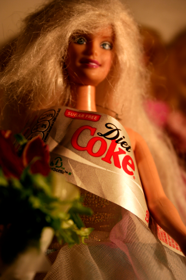 Eine Puppe mit einem "zuckerfreier diet coke" Anhänger.