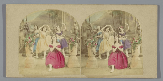 Ein Schwarz-Weiß-Foto einer Gruppe von Frauen in pinken Kleidern, die auf einer geschmückten Bühne tanzen, mit Blumenvasen und grünen Bäumen im Hintergrund.